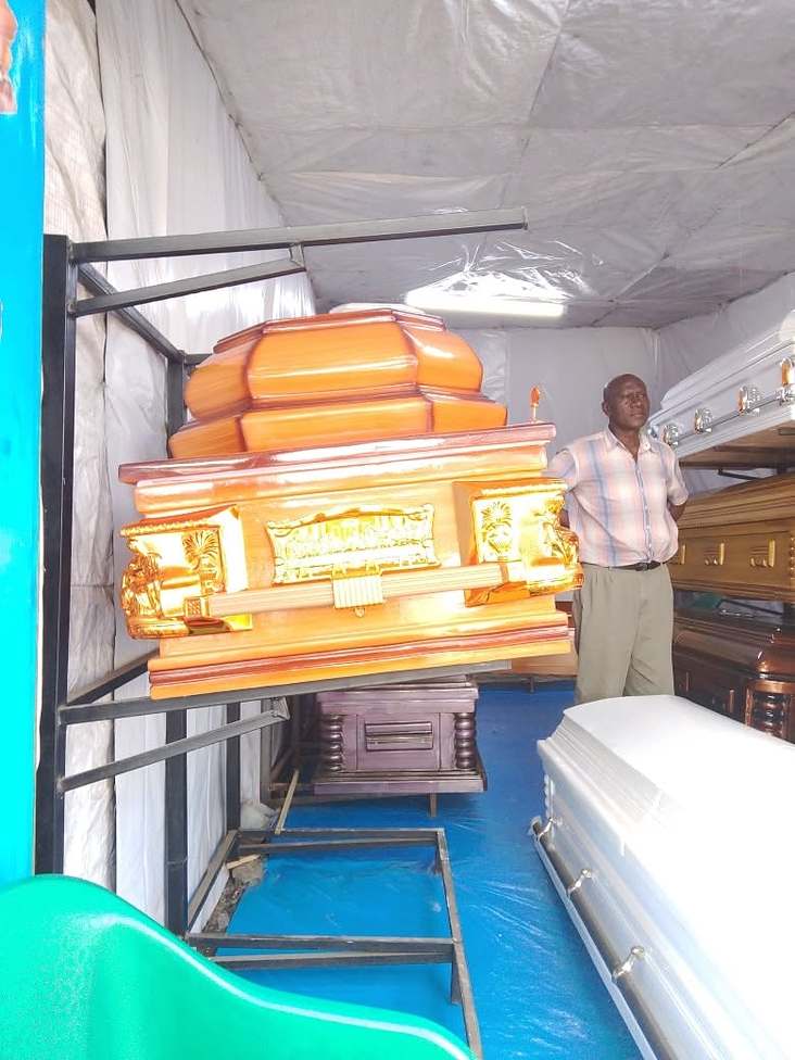 An ornate orange-finish casket in a coffin showroom