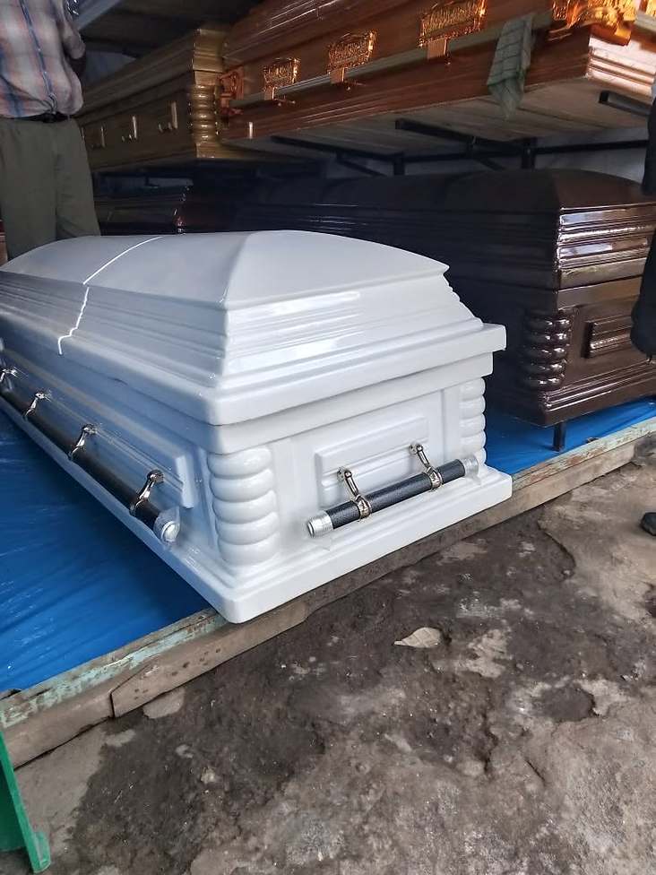 A white casket on display in a coffin showroom